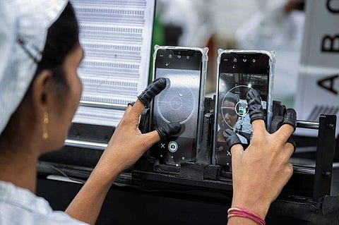 An employee tests the camera of a mobile phone. (Photo | Bloomberg)