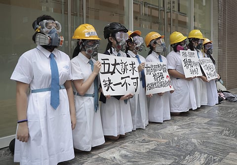 Students wearing gas masks and helmets hold a banner which reads 'Five major demands are indispensable.', at St. Francis' Canossian College in Hong Kong, on Monday, Sept. 2, 2019. (Photo | AP)