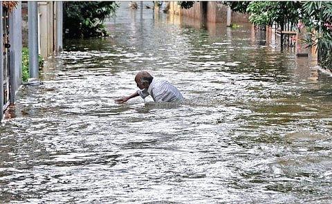 A man wades past floodwaters at Malkajgiri (Photo |EPS)