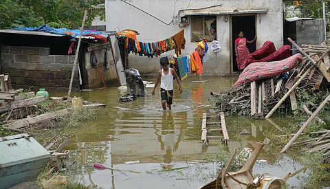 A boy wades through the water just outside his house after Hulimavu lake breach. (File Photo | Meghana Sastry, EPS)