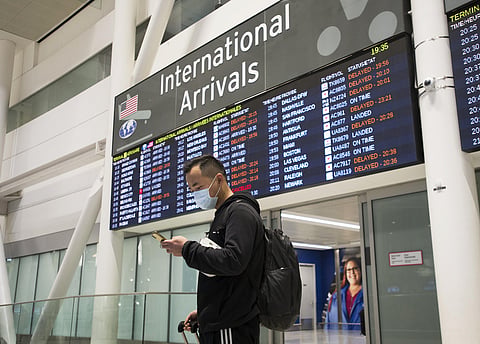 A man wears a masks following the outbreak of a new virus as people arrive from the International terminal at Toronto Pearson International Airport in Toronto on Saturday, Jan. 25, 2020. 