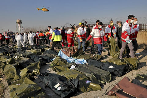 Rescue workers recover bodies of victims at the scene where a Ukrainian plane crashed in Shahedshahr, southwest of Tehran. (Photo | AP)