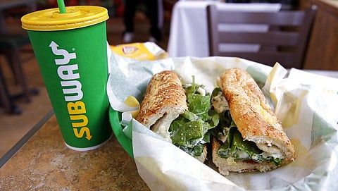 The Subway logo is seen on a soft drink cup next to a sandwich at a restaurant. (Photo | AP)