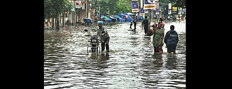 People wade through ankle-deep water  on a busy road in city I Express