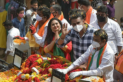 Sandalwood actors Amulya and Darshan greet voters during a roadshow for BJP’s RR Nagar candidate N Muniratna, in Bengaluru on Friday.  (Photo| Meghana Sastry, EPS)