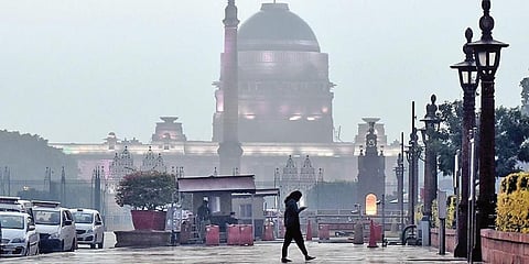 A pedestrian walks in the rain near North Block in New Delhi. (Photo | Praveen Negi, EPS)