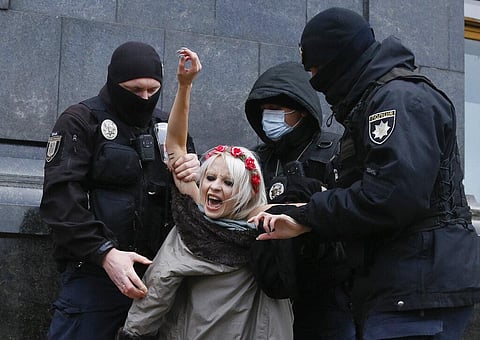 Police detain an activist from Ukrainian female rights organization 'Femen' on the International Day for the Elimination of Violence against Women as she protested naked 
