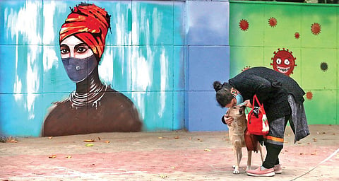 A woman wearing a mask walks past a mural on novel coronavirus and protective measures in New Delhi. (Photo | Shekhar Yadav, EPS)