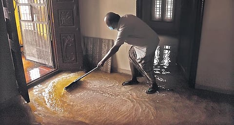 Damodharan, a resident of Madippakkam, sweeps out flood water inside  his house on Thursday | Ashwin Prasath