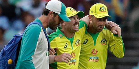 Australia's David Warner (C) is assisted from the field after injuring himself while fielding during the ODI match against India at the Sydney Cricket Ground. (Photo | AP)