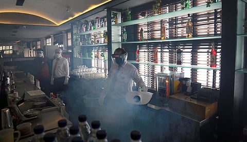 An employee wearing a face shield sanitizes an alcohol cabinet. (Photo | EPS/Shekhar Yadav)