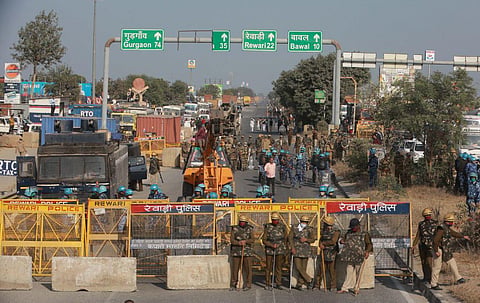 Police personnel stand along a highway on the Haryana-Rajasthan border to stop farmers from joining protests in Delhi.