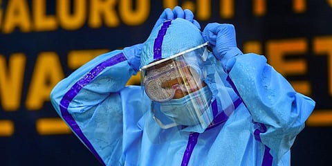 A health worker adjusts his face shield as he prepares to collect swab samples of people for COVID-19 test. (File Photo | PTI)