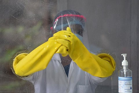 A health worker waits to collect swab samples from residents to test for the Covid-19 coronavirus. (Photo| AFP)