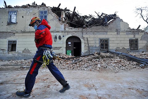 A rescuer walks past a building damaged in an earthquake in Petrinja, Croatia, Tuesday, Dec. 29, 2020. (Photo | AP)