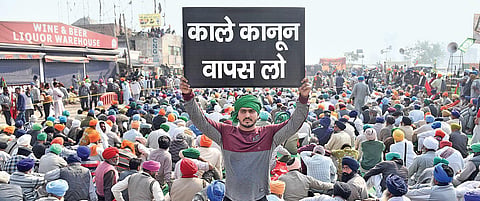A farmer puts up a placard at the Singhu border in New Delhi on Wednesday demanding rollback of the three newly enacted central farm legislations | Parveen Negi