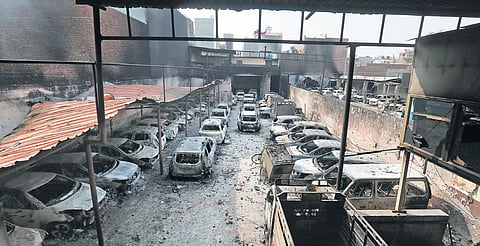 Charred vehicles at a parking lot near Usmanpur; a woman watches policemen; firemen at Gokulpuri; a family on scooter passes by security personnel at Baburpur |  (PHOTO | SHEKHAR YADAV, EPS)