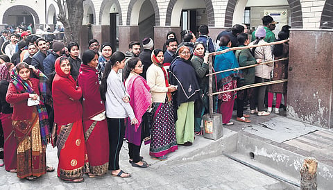 People check their name in a voter list outside a polling station during the during the Delhi Assembly elections at Satbadi area in New Delhi on Saturday. (Photo|EPS/ Shekhar yadav)