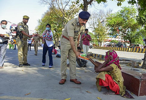 ADG Prem Prakash and other police personnel distribute food to homeless people in Prayagraj. (Photo | PTI)