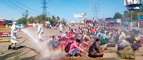 Migrant labourers who de-boarded a bus from Delhi being sprayed with chemicals at Bareilly, UP on Monday