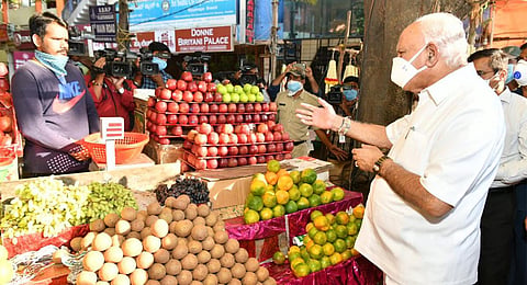 CM B S Yediyurappa inquires with a fruit seller about his daily business amidst the lockdown, during his visit to Vijayanagar Market in Bengaluru on Sunday | Express