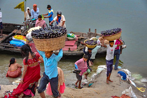 Farmers arriving by a boat carry their vegetables to a wholesale market during ongoing COVID-19 lockdown in Patna. (Photo | PTI)
