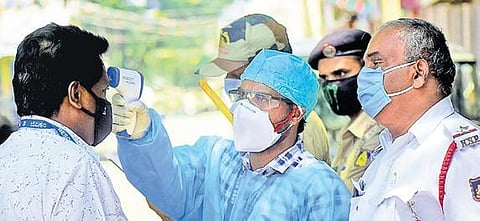 A health worker screens a Bescom staffer using a thermal device at Padarayanapura in Bengaluru on Wednesday. The ward has been identified as a COVID hotspot and sealed off | Pandarinath b