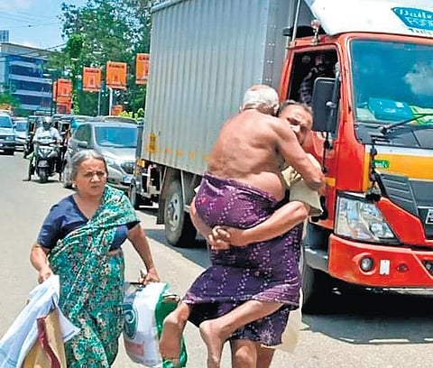 Roy walks towards his autorickshaw carrying father George on his shoulders (Photo | EPS)