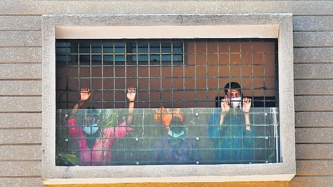 Migrants workers peer out the window of a hostel they’re being housed at temporarily in Bengaluru | SHRIRAM BN