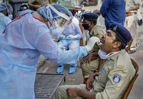 A healthcare worker collects swab sample of a policeman for COVID-19 test during the nationwide lockdown in Ahmedabad. (Photo | PTI)