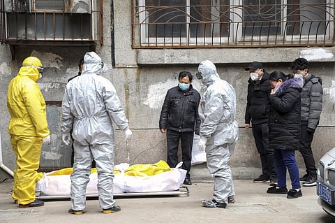 In this Feb. 1, 2020, file photo, funeral home workers remove the body of a person suspected to have died from the coronavirus outbreak from a residential building in Wuhan in central China's Hubei Province. (Photo | AP)