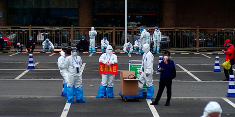 orkers in full protective gear stand in a parking lot of the West Station in Beijing, China. (File photo| AP)
