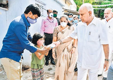 Chief Minister BS Yediyurappa distributes milk packets to residents  of Ashwath Nagar, Bengaluru, on Thursday | Express