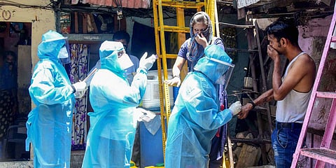 Health workers wearing protective suits screen resident of Kumbharwada during a house-to-house health survey at Mumbai's Dharavi. (Photo| PTI)
