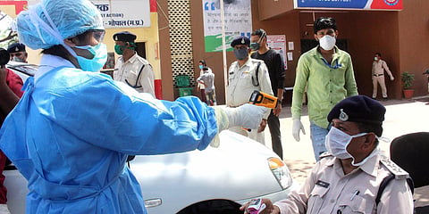 A doctor uses thermal screening on police personnel at Jahangirabad police station after security personnel tested positive for COVID-19, in Bhopal. (Photo| ANI)