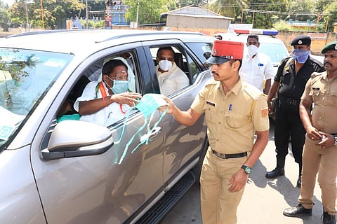 CM Narayanasamy handing over a mask to a policeman on duty in Puducherry. (Photo | EPS)