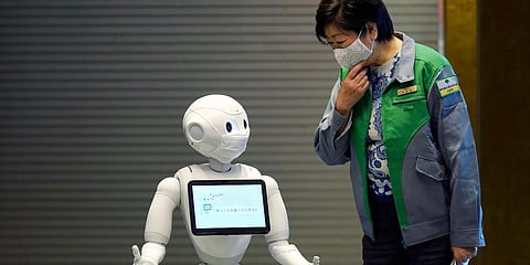 A humanoid robot Pepper wearing a face mask greets Tokyo Governor Yuriko Koike at the lobby of a hotel for COVID-19 patients with mild symptoms during a media preview in Tokyo. (Photo| AP)