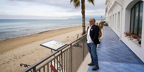 A man looks at the empty beach from the terrace of his hotel, in Sperlonga in Italy. (Photo| AP)