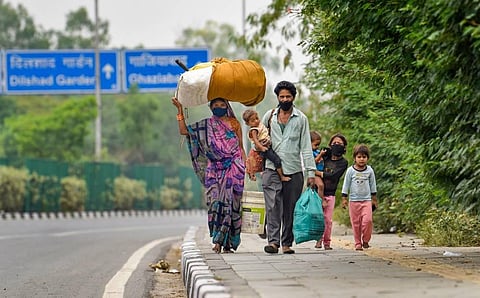 Migrant labourer Achhalal with his family walks along a road to reach Sarai Kale Khan for travelling back to his native place Madhya Pradesh during the ongoing COVID-19 lockdown at Anand Vihar in New Delhi Wednesday. (Photo | PTI)