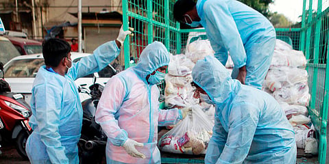 People wear protective suits as they distribute grocery packets in Mumbai. (FIle photo| ANI)