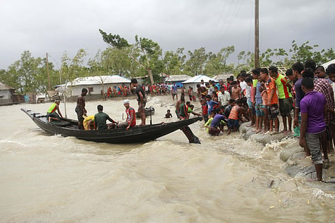 A boat brings people to land as locals check an embankment before Cyclone Amphan made landfall in Shyamnagar Shatkhira Bangladesh. (Photo | PTI)