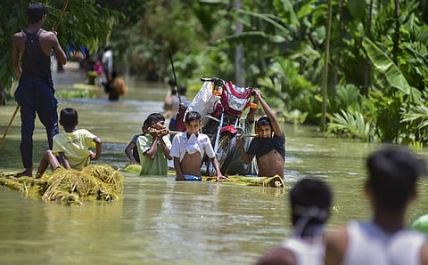Villagers carry a bike on a banana raft in flood-hit locality of Doboka in Hojai district of Assam. (Photo | PTI)