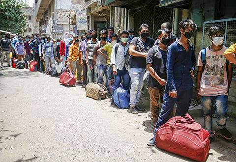Migrants stand in a queue to board a train to West Bengal outside the railway station during the nationwide COVID-19 lockdown in Ahmedabad Saturday May 30 2020. (Photo | PTI)