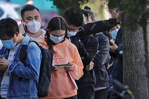 People wearing protective face masks to prevent the spread of the new coronavirus wait in a queue to get temperature check and the health code in Beijing, China. (File Photo | AP)