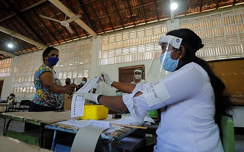 A polling officer issues a ballot paper to a voter during a mock election ahead of Sri Lanka's parliamentary poll. The country's Election Commission set August 5 as the new date for parliamentary elections after postponing them twice over the coronavirus 