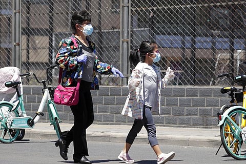 A woman and a child wearing protective face masks and gloves to help curb the spread of the new coronavirus arrive to a stadium to get a nucleic acid test in Beijing, Sunday, June 14, 2020. China is reporting its highest daily total of coronavirus cases i