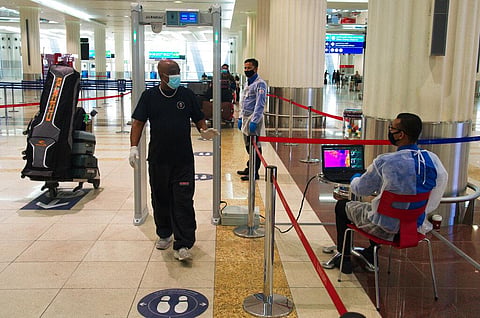 A passenger wearing a mask due to the coronavirus pandemic passes through a temperature screening at Dubai International Airport. (Photo | AP)