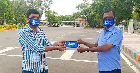Actor Rajinikanth's fans holding and wearing masks with his photo and a political message