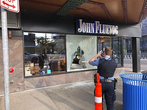 A police officer takes photos Sunday, June 21, 2020, of a shattered window of a shoe store that was hit by gunfire in Minneapolis' Uptown neighborhood. Multiple people were shot, one fatally, when gunfire broke out shortly after midnight Sunday. (Photo | 