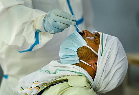 A medic takes swab samples for COVID-19 infection from a man at a testing centre inside a government school in New Delhi Monday June 22 2020. (Photo | PTI)
